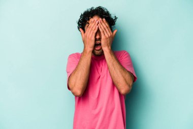 Beyaz arka planda izole edilmiş genç beyaz bir adam yüzünün yarısını palmiye ile örterek eğleniyor..