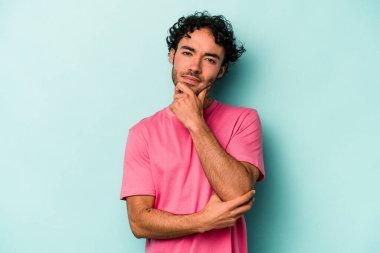 Beyaz arka planda izole edilmiş genç beyaz bir adam şüpheli, belirsiz, seni muayene ediyor..