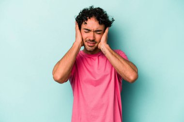 Beyaz arka planda izole edilmiş genç beyaz bir adam kulaklarını elleriyle kapatıyor..
