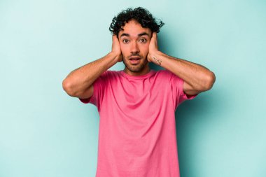 Beyaz arka planda izole edilmiş genç beyaz bir adam kulakları kulaklarıyla kapatıyor ve çok ses duymamaya çalışıyor..