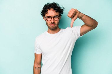 Beyaz arka planda izole edilmiş genç beyaz bir adam baş parmağını aşağı gösteriyor ve hoşlanmadığını ifade ediyor..