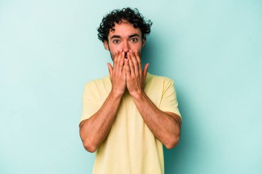 Beyaz arka planda izole edilmiş genç beyaz adam elleriyle ağzını kapatırken şok oldu..