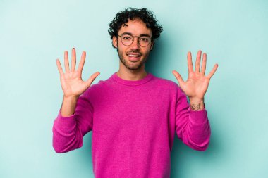 Beyaz arka planda izole edilmiş beyaz tenli genç adam on numarayı elleriyle gösteriyor..