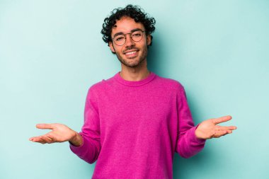 Beyaz arka planda izole genç beyaz adam kollarıyla ölçek yapar, mutlu ve kendinden emin hisseder..