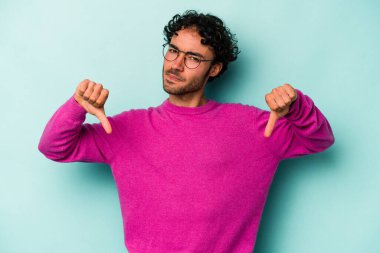 Beyaz arka planda izole edilmiş genç beyaz adam baş parmağını aşağı gösteriyor, hayal kırıklığı konsepti..