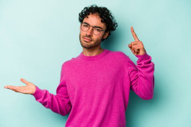 Beyaz arka planda izole edilmiş genç beyaz bir adam elinde bir ürün tutuyor ve.