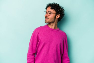 Beyaz arka planda izole edilmiş genç beyaz adam gevşemiş ve mutlu bir şekilde gülüyor, boynunda dişlerini gösteriyor..