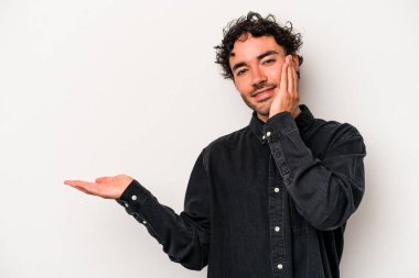 Beyaz arka planda izole edilmiş genç beyaz bir adam bir avuç içinde fotokopi alanı tutuyor, el üstünde tutuyor. Şaşırmış ve mutlu..