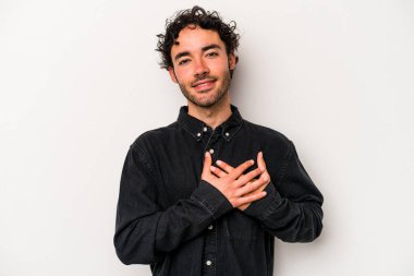 Beyaz arka planda izole edilmiş beyaz tenli genç bir adam, dostane bir ifadeye sahip, avuçlarını göğsüne bastırıyor. Aşk konsepti.