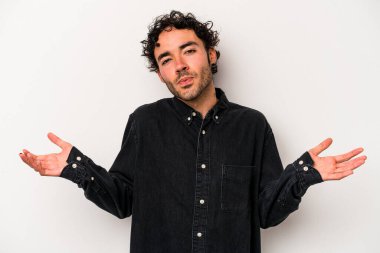 Beyaz arka planda izole edilmiş genç beyaz bir adam sorgulama sırasında omuz silkiyor ve şüphe duyuyor..