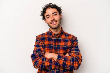 Beyaz arka planda kendini güvende hisseden, kararlılıkla kollarını kavuşturan beyaz tenli genç bir adam..