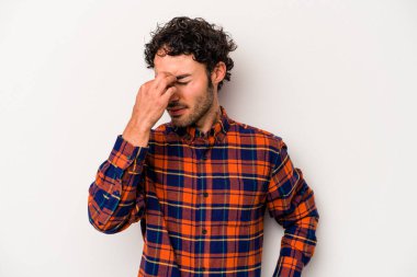 Beyaz arka planda izole olmuş genç beyaz bir adam başı ağrıyor, yüzüne dokunuyor..