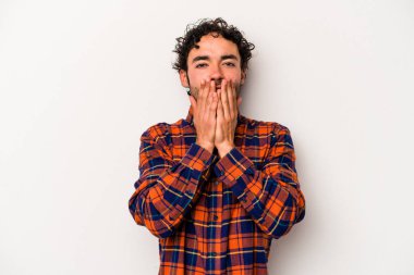 Beyaz arka planda izole edilmiş genç beyaz adam şok olmuş, ağzı ellerle kaplanmış, yeni bir şey keşfetmeye hevesli..