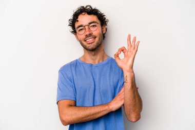 Beyaz arka planda izole edilmiş genç beyaz bir adam bir göz kırptı ve elleriyle iyi bir jest yaptı..