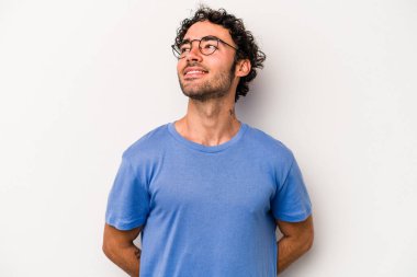 Beyaz arka planda izole edilmiş genç beyaz adam gevşemiş ve mutlu bir şekilde gülüyor, boynunda dişlerini gösteriyor..