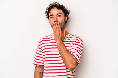 Beyaz arka planda izole edilmiş genç beyaz adam şok olmuş, ağzı ellerle kaplanmış, yeni bir şey keşfetmeye hevesli..