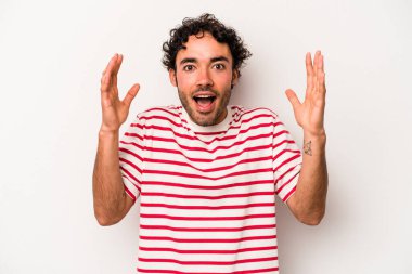 Beyaz arka planda izole genç beyaz adam hoş bir sürpriz alıyor, heyecanlı ve el kaldırıyor..