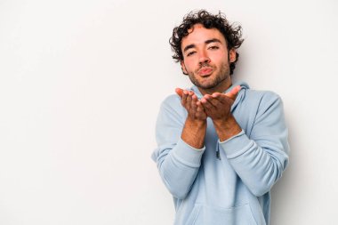 Beyaz arka planda izole edilmiş genç beyaz bir adam dudaklarını katlıyor ve hava öpücüğü vermek için avuç içleri tutuyor..