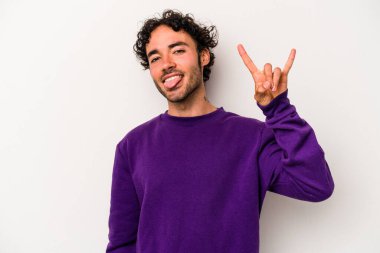 Beyaz arka planda izole edilmiş genç beyaz bir adam parmaklarıyla kaya hareketi gösteriyor.