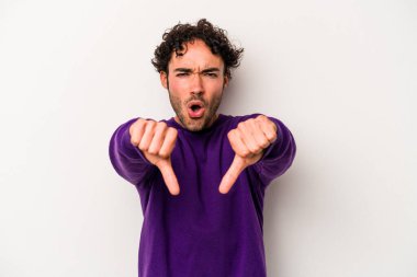 Beyaz arka planda izole edilmiş genç beyaz bir adam baş parmağını aşağı gösteriyor ve hoşlanmadığını ifade ediyor..
