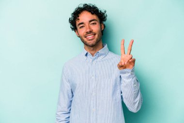 Beyaz arka planda izole edilmiş genç beyaz bir adam zafer işareti gösteriyor ve gülümsüyor..