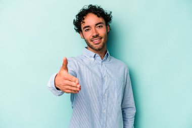 Beyaz arka planda izole edilmiş genç beyaz bir adam selamlama jesti olarak kameraya elini uzatıyor..