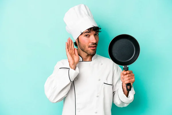 年轻的高加索厨师拿着一只被蓝色背景隔离的飞碟 想听一些闲话 — 图库照片