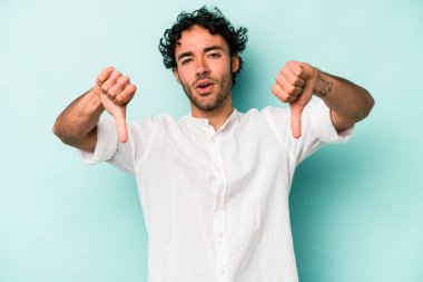 Beyaz arka planda izole edilmiş genç beyaz bir adam baş parmağını aşağı gösteriyor ve hoşlanmadığını ifade ediyor..