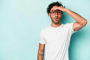 Beyaz arka planda izole edilmiş genç beyaz bir adam uzaklara bakıyor ve elini alnına koyuyor..