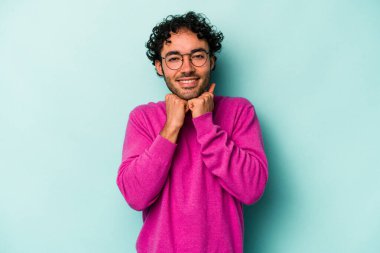 Beyaz arka planda izole genç beyaz adam ellerini çenesinin altında tutuyor, mutlu bir şekilde yana bakıyor..