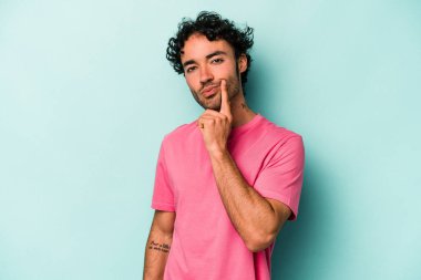 Beyaz arka planda izole edilmiş genç beyaz adam alaycı bir ifadeyle kameraya bakıyor..