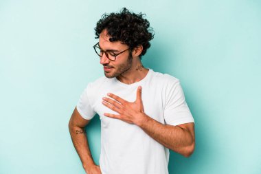 Beyaz arka planda soyutlanmış beyaz tenli genç bir adam gülüyor, elini yüreğine koyuyor, mutluluk kavramını koruyor..