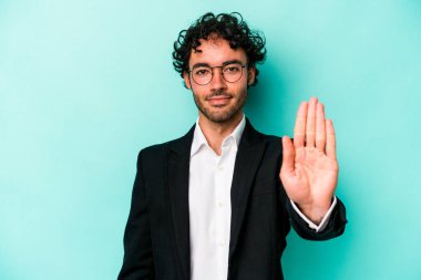Kafkasyalı genç iş adamı mavi arka planda izole edilmiş, elini uzatmış, dur işaretini göstererek seni engelliyor..