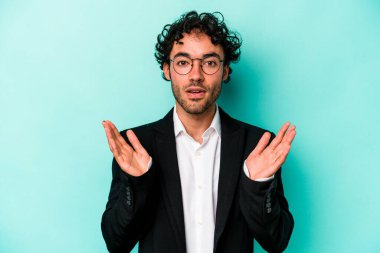 Kafkasyalı genç iş adamı mavi arka planda izole edilmiş şaşırmış ve şok olmuş..