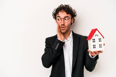 Beyaz arka planda izole edilmiş oyuncak evi tutan Kafkasyalı genç bir iş adamı gizli bir fren haberinin olduğunu söylüyor.