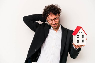 Beyaz arka planda izole edilmiş bir oyuncak evi tutan Kafkasyalı genç iş adamı kafasının arkasına dokunuyor, düşünüyor ve bir seçim yapıyor..