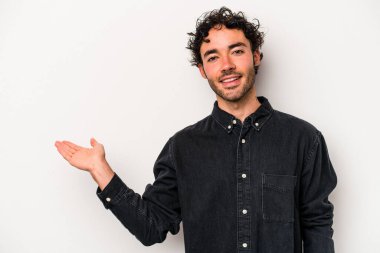 Beyaz arka planda izole edilmiş genç beyaz bir adam bir palmiye üzerinde fotokopi alanı gösteriyor ve belinde başka bir el tutuyor..