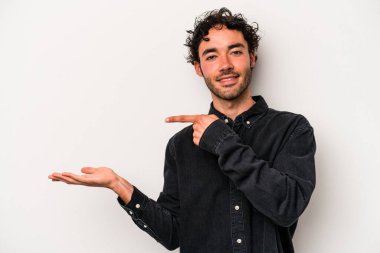 Beyaz arka planda izole edilmiş genç beyaz bir adam, palmiye üzerinde bir fotokopi alanı tutarken heyecanlı..