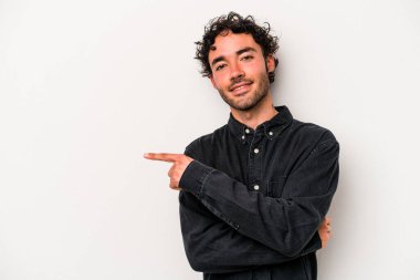 Beyaz arka planda izole edilmiş genç beyaz adam işaret parmağıyla işaret ederek gülümsüyor..