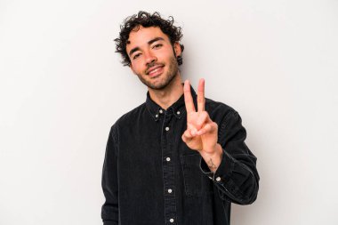 Beyaz arka planda izole edilmiş genç beyaz bir adam zafer işareti gösteriyor ve gülümsüyor..