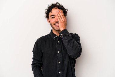 Beyaz arka planda izole edilmiş genç beyaz bir adam yüzünün yarısını palmiye ile örterek eğleniyor..