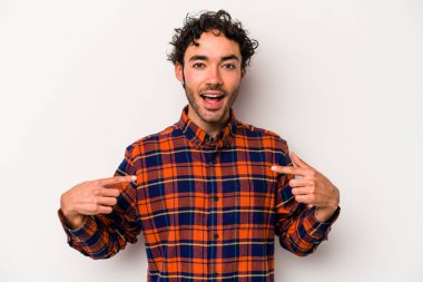 Beyaz arka planda izole edilmiş genç beyaz bir adam parmağını göstererek şaşırdı, geniş bir gülümsemeyle..