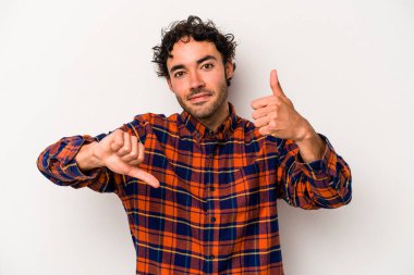 Beyaz arka planda izole edilmiş genç beyaz bir adam baş parmaklarını aşağı ve yukarı kaldırıyor, zor seçim konsepti