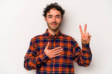 Beyaz arka planda izole edilmiş genç beyaz adam yemin ediyor, elini göğsüne koyuyor..