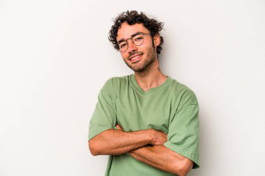 Beyaz arka planda kendini güvende hisseden, kararlılıkla kollarını kavuşturan beyaz tenli genç bir adam..