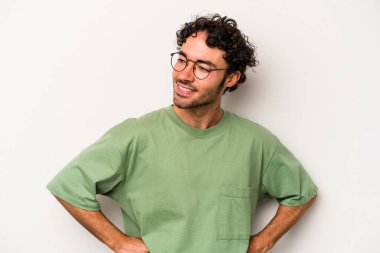 Beyaz arka planda izole genç beyaz adam mutlu bir şekilde gülüyor ve ellerini karnının üstünde tutarak eğleniyor..