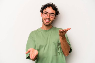 Beyaz arka planda izole genç beyaz adam kollarıyla ölçek yapar, mutlu ve kendinden emin hisseder..