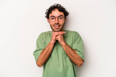 Beyaz arka planda izole edilmiş genç beyaz bir adam şans için dua ediyor, şaşırmış ve ağzını açıp önüne bakıyor..