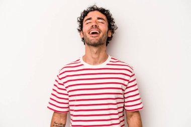 Beyaz arka planda izole edilmiş genç beyaz adam gevşemiş ve mutlu bir şekilde gülüyor, boynunda dişlerini gösteriyor..