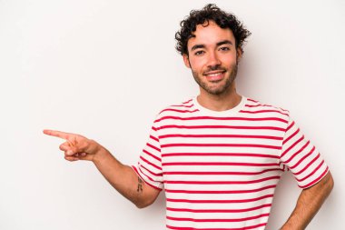 Beyaz arka planda izole edilmiş genç beyaz adam işaret parmağıyla işaret ederek gülümsüyor..